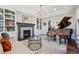 Cozy living room featuring a fireplace, built-in shelving, and a grand piano creating a warm and inviting ambiance at 10660 Weathersfield Ct, Highlands Ranch, CO 80129