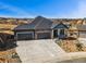 Aerial view of a gray home with stone accents, three-car garage, and well-kept front yard at 3884 Freestone Pt, Castle Rock, CO 80108