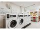 Community laundry room with coin operated machines, folding table, and fan, providing an on-site laundry solution at 635 S Alton Way # 1C, Denver, CO 80247