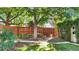 Beautifully landscaped backyard with wooden fence, mature trees, and a charming brick outbuilding at 926 S Fillmore Way, Denver, CO 80209