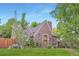 A brick home featuring a beautiful roof line, mature landscaping, and a lush green lawn at 926 S Fillmore Way, Denver, CO 80209