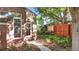 Landscaped side yard with stone path, brick house corner and lush green foliage at 926 S Fillmore Way, Denver, CO 80209