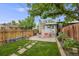 Private backyard features a patio area, green lawn, mature tree, and wood fence at 194 S Emerson St, Denver, CO 80209