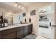 Modern bathroom with dual sinks, granite countertops, dark cabinets, and an open doorway to bedroom at 25128 E Maple Ave, Aurora, CO 80018