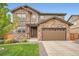 Charming two-story home showcasing a stone facade, attached garage, and well-maintained front yard at 25128 E Maple Ave, Aurora, CO 80018