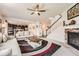 Open concept living room with fireplace, ceiling fan, staircase, and view of the kitchen at 25128 E Maple Ave, Aurora, CO 80018