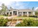 An elegant home showcasing a landscaped yard, a picturesque pond, and an inviting covered porch with stone accents at 5425 S University Blvd, Greenwood Village, CO 80121