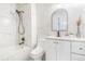 Bright bathroom featuring marble tile, bathtub with shower, updated vanity, and modern arched mirror at 18751 E Mexico Ave, Aurora, CO 80017