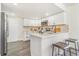 Well-lit kitchen with white cabinets, modern appliances, and a breakfast bar with seating at 18751 E Mexico Ave, Aurora, CO 80017