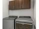 Modern laundry room equipped with Whirlpool washer and dryer units and overhead storage cabinets at 10226 Worchester St, Commerce City, CO 80022