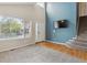 Bright living room with vaulted ceilings, large window, modern tv wall, and carpeted stairs at 10517 Madison St, Thornton, CO 80233