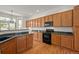 Updated kitchen featuring wood cabinets, granite countertops, and modern, black appliances at 14447 Inca Ct, Westminster, CO 80023
