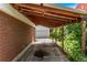 A covered carport area with a brick wall and a garage in the background at 3182 W Radcliff Dr, Englewood, CO 80110