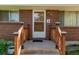 Close-up of the brick facade and entrance with wood railing at 3182 W Radcliff Dr, Englewood, CO 80110