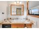 Bright bathroom features a wood-trimmed mirror, vanity and window with blinds at 3260 Bit Rd, Evergreen, CO 80439