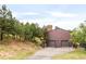 Multi-car garage with paved driveway and surrounding hillside with mature trees at 3260 Bit Rd, Evergreen, CO 80439