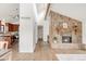 Bright living room featuring a stone fireplace, hardwood floors, and views of the kitchen at 3260 Bit Rd, Evergreen, CO 80439