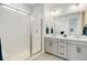 Bathroom featuring dual vanity sinks, and walk-in shower with tiled surround at 7029 Sagerock St, Castle Pines, CO 80108