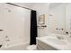 Clean bathroom with tile tub surround, gray vanity, and ample lighting at 7029 Sagerock St, Castle Pines, CO 80108