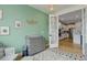 Bedroom with a mint accent wall, gray dresser, and view into the modern kitchen at 7029 Sagerock St, Castle Pines, CO 80108