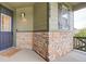 Inviting home entryway featuring brick accents, a covered porch, and stylish outdoor lighting at 7029 Sagerock St, Castle Pines, CO 80108