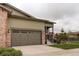 Exterior view of home featuring a two car garage, stone accents, and manicured landscaping at 7029 Sagerock St, Castle Pines, CO 80108