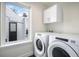 Bright laundry room with a window, modern washer and dryer, and built-in storage cabinets at 1169 S Reed Way, Lakewood, CO 80232