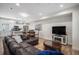 Open-concept living room with modern fixtures, hardwood floors, leather sectional, and sleek entertainment center at 1169 S Reed Way, Lakewood, CO 80232