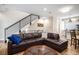 Cozy living room featuring a dark leather sectional sofa, hardwood floors, and stylish staircase at 1169 S Reed Way, Lakewood, CO 80232