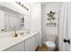 Bright bathroom featuring a white vanity with mirror, toilet, and stylish floating shelves at 6742 Cole Cir, Arvada, CO 80004
