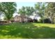 Backyard view of home with brick chimney, and wooden deck, nestled among mature trees at 6742 Cole Cir, Arvada, CO 80004