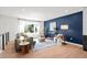 Stylish living room with a bold blue accent wall, hardwood floors, and large windows offering scenic outdoor views at 6742 Cole Cir, Arvada, CO 80004