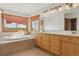 Bathroom with large soaking tub, tile surround, and a double vanity, all complemented by natural light from large windows at 371 Buckskin Ct, Parker, CO 80138
