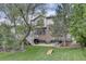 Spacious backyard featuring a stone-clad house, mature trees, deck with stairs, patio, and a lush green lawn at 24556 E Ottawa Ave, Aurora, CO 80016