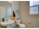 Small bathroom featuring a pedestal sink, toilet, mirror, and window at 24556 E Ottawa Ave, Aurora, CO 80016