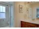 Bright bathroom with cherry wood cabinetry, glass enclosed shower, and large vanity mirror at 24556 E Ottawa Ave, Aurora, CO 80016