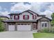 Charming two-story home featuring a stone facade, three-car garage, and striking red shutters at 24556 E Ottawa Ave, Aurora, CO 80016