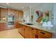 Large kitchen island with sink, wooden cabinetry, and view to the stairs at 24556 E Ottawa Ave, Aurora, CO 80016