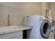 Laundry room with granite counters, sink, and white front-load washer and dryer at 24556 E Ottawa Ave, Aurora, CO 80016