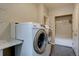 Bright laundry room with white front-load washer and dryer and storage at 24556 E Ottawa Ave, Aurora, CO 80016