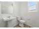 This bathroom has a pedestal sink and a toilet under a bright window at 2070 Wagon Wheel Aly, Brighton, CO 80601