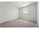 An empty carpeted bedroom features neutral colors and a view of the outdoors at 2070 Wagon Wheel Aly, Brighton, CO 80601