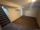 Unfinished basement featuring carpeted floor and a partial view of the stairs in this fixer-upper at 7810 Pontiac St, Commerce City, CO 80022