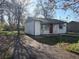 Charming single story home featuring a red front door, light blue trim and siding, set back from the street in an overgrown yard at 7810 Pontiac St, Commerce City, CO 80022