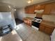 Kitchen with wood cabinets, tile flooring, laminate counters, and white appliances in a home that needs some TLC at 7810 Pontiac St, Commerce City, CO 80022