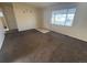 This living room features brown carpet, tile accent at entry and a view to the front yard from the large window at 7810 Pontiac St, Commerce City, CO 80022