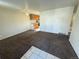 Neutral living room featuring brown carpet, ceiling fan, and tile accent, leading into the kitchen in this home at 7810 Pontiac St, Commerce City, CO 80022