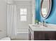 A white bathroom with vanity, tub shower, and blue accent wall at 2703 N Milwaukee St, Denver, CO 80205