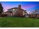 Expansive backyard features lush green lawn, brick patio, and outdoor fireplace, perfect for entertaining at 15407 E Crestline Pl, Centennial, CO 80015