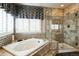 Well-appointed bathroom with soaking tub, glass shower, tiled accents, and bright window with shutters at 15407 E Crestline Pl, Centennial, CO 80015